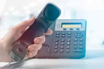 contact us. office voip phone with handset up on table with blurred office background....