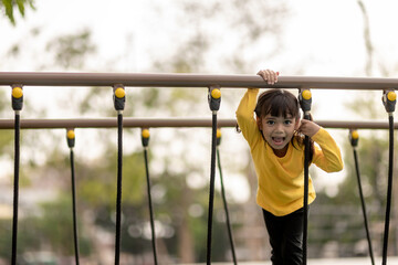 Fototapeta premium Asian little girl enjoys playing in a children playground, Outdoor portrait