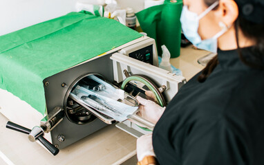 A dentist sterilizing his tools, Dentist with a dental sterilizer,  A dentist with a dental...