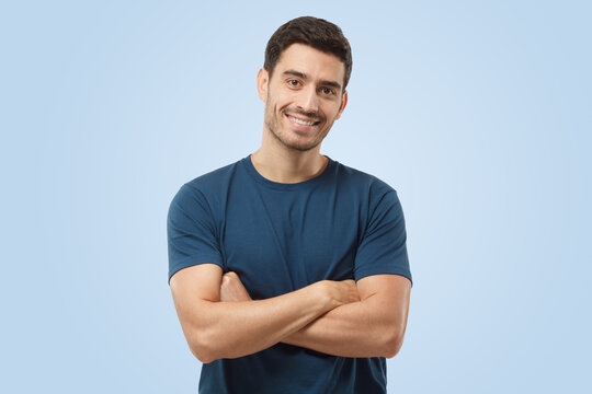Attractive smiling handsome man in blue t-shirt standing with crossed arms