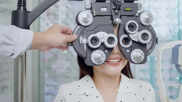 Young female customer being examined visual test using Bifocal Optometry eyesight measurement device by ophthalmologist in optical center, eyecare concept.