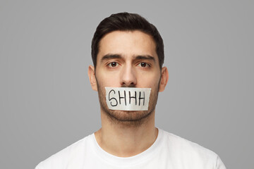 Young man with taped mouth with shhh text on it