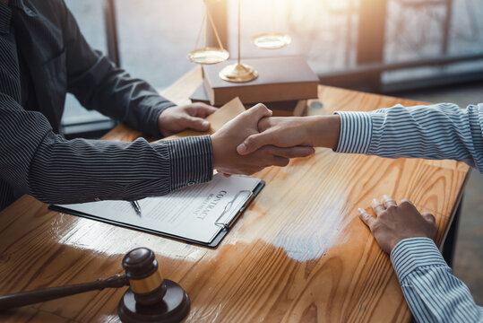 Businessman shaking hands partner lawyers or attorneys discussing a contract agreement.