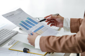 Business woman pointing to a graph of financial data to plan investments in business market.