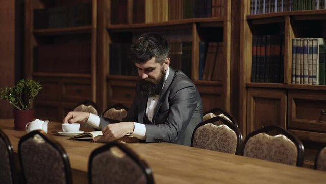 Businessman in classic suit read book. Old fashion business people. Bearded man in classic suit with cup of english tea. Mature man enjoys reading.
