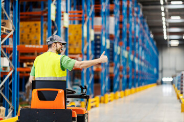 Rear view of a warehouse worker driving forklift and giving thumbs up.