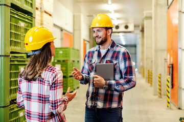 Coworkers standing in factory and discussing about progress.