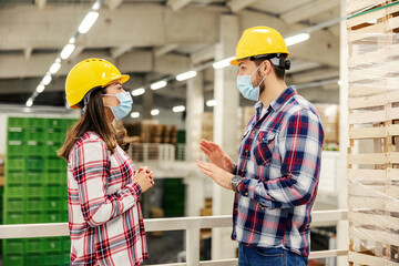 Warehouse worker listening to a supervisor explaining productivity during corona virus.