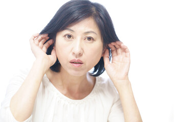 不快そうに耳に手をやる中年女性　