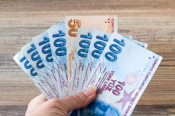 One hand holding Turkish Hundred and Fifty Banknotes on wooden surface