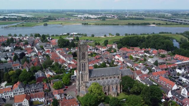 High altitude aerial drone footage of the Saint Martin church in Zaltbommel is a municipality and a city in the Netherlands in the background showing Waal river a branch of river Rhine 4k resolution