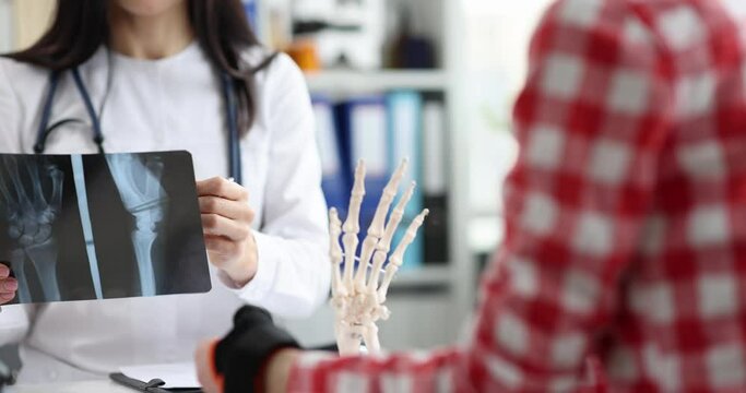 Doctor talks to patient with injured arm and shows x-ray