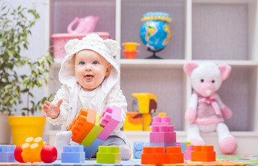 Fototapeta na wymiar baby girl playing with colourful building blocks at home or kindergarten