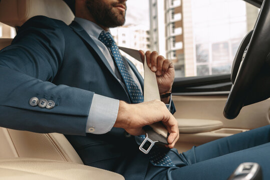 Businessman in formal wear unbuckling after driving car