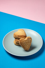 Shortbread cookies in a plate on a colored background. Heart shaped cookies.