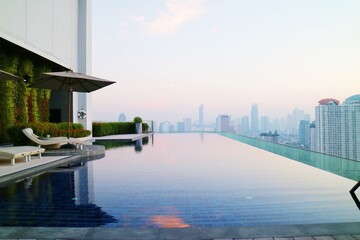 Swimming pool view on top floor of stylish upscale hotel in Bangkok, Thailand - obrazy, fototapety, plakaty