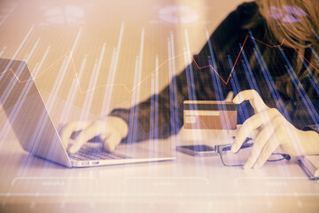 Double exposure of woman on-line shopping holding a credit card and financial graph drawing. Stock market E-commerce concept.