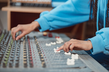 Female sound engineer, musician producer hands using mixing board and software to create song in...