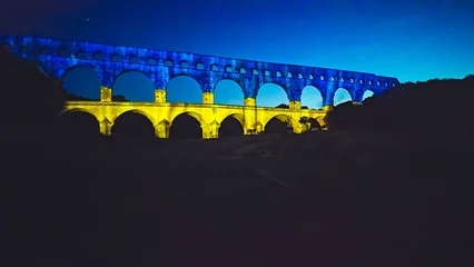 Papier Peint photo Pont du Gard Pont du Gard bridge with Ukraine flag in support of the invasion of Ukraine and its joining the European Union. Roman aqueduct of Nimes city in France in the night sky.