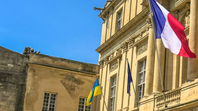 The Ukraine flag and European flag with France flag at the window waving united in support of the invasion of Ukraine and its joining the European Union. Europeans support Ukraine joining the EU.