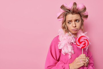 Upset thoughtful woman has leaked makeup holds round lollipop on stick keeps to diet cannot eat...