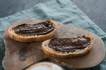 Organic chocolate hazelnut spread on ciabatta slices on wood board