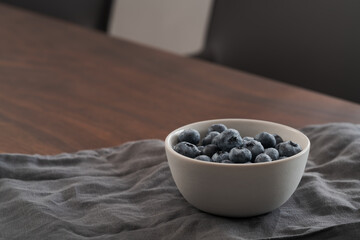 Fototapeta na wymiar Fresh washed blueberries in white bowl on linen napkin