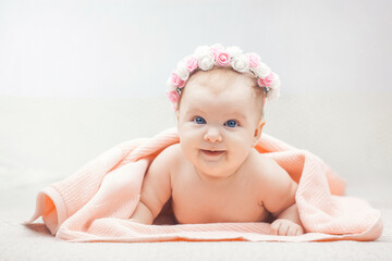 Cute baby with flower wreath. three month old blue-eyed girl wrapped in a terry towel