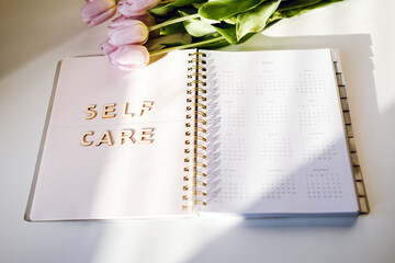 Self Care, wellbeing concept with open notebook, Self care word, tulip flowers on white table. Take care of yourself, Beauty, self care routine - obrazy, fototapety, plakaty
