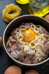 Close-up of pasta alla carbonara served with an egg yolk, vertical shot, selective focus