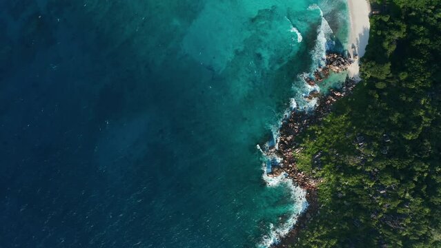 Aerial flat slider along the coastline blue lagoon Anse Cocos beach