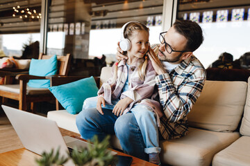 happy dad and daughter with laptop and headphones