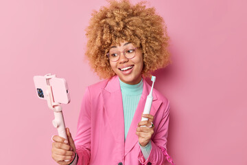 Pretty female blogger shows her morning routine during blog live stream brushes teeth with modern...