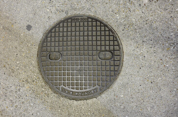 Smiling rusty manhole cover made of iron.
