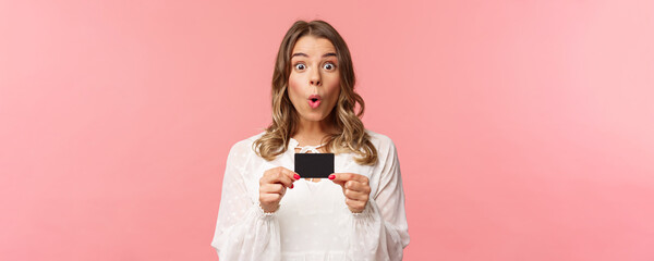 Close-up portrait of excited and amused young girl describe new features of her bank, received new...
