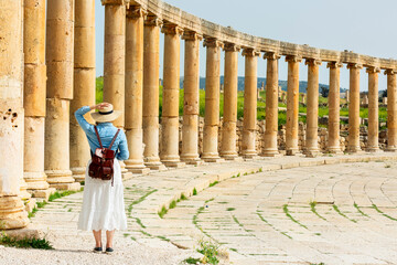 young woman tourist in color dress and hat leading man to South gate of the Ancient Roman city of...
