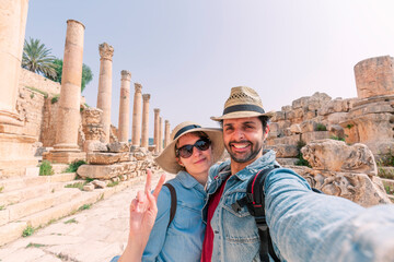 a young couple with hat taking a selfie while enjoying the beautiful landscape of the ancient ruins...