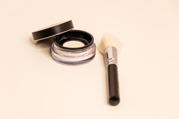 Presentation of the brand and packaging. Professional face powder with a light brush on a white background. Foundation for the face. Cosmetic products. Close-up. View from above. Place to copy.