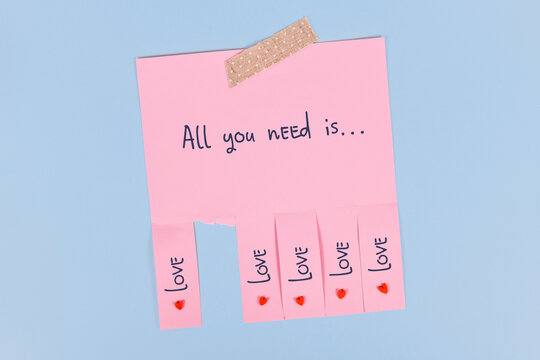 Tear off stub note with text 'All you need is love' on pink paper