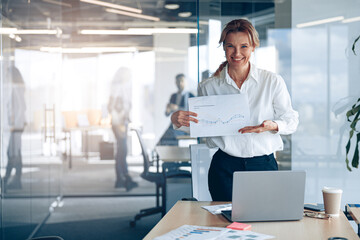 Positive mature businesswoman showing her new plans with graph in modern office 