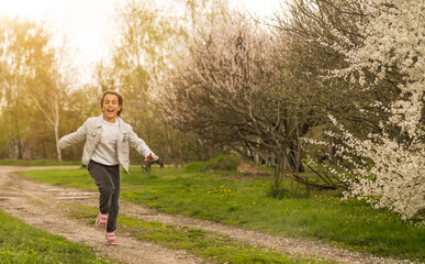 Happy little girl playing in spring cherry garden.