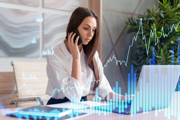 Attractive businesswoman in white shirt has conference call to optimize trading strategy at corporate finance fund. Forex chart hologram over office background