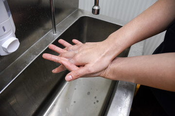 Woman washing hands in a sink with soap.