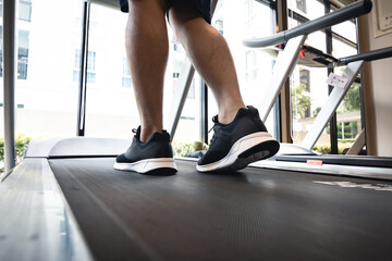 Fototapeta na wymiar Man legs with sport shoes running on treadmill in fitness gym.