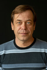 Portrait of a happy blue-eyed man 45-50 years old in a golf sweater on a black background, Perhaps he is a former military man or businessman, lawyer or charismatic actor.