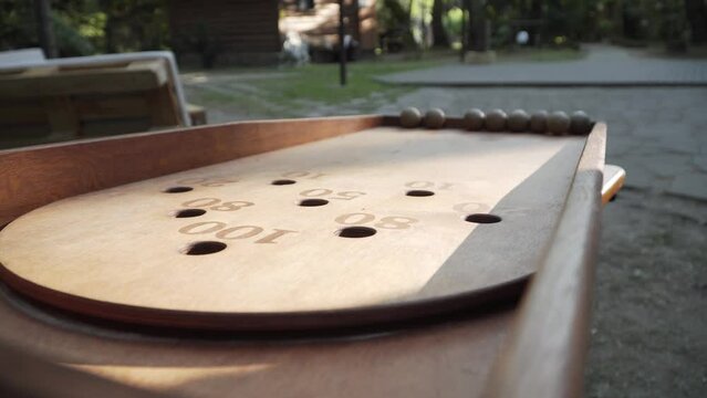 Women hands roll up lot of balls down wooden board of Japanese billiards to start the game. Preparing for game of culbuto in green yard, close-up, static frame.