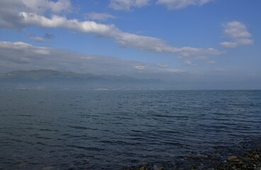 The city in the cap of fog on the coast of the sea. Spring day. Sunset. Black Sea. Novorossiysk. Russia.