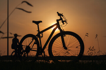 Obraz premium A silhouette of a bike at sunset. The sun shines through the bicycle frame, selective focus