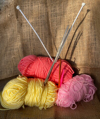 Multi-colored threads and knitting needles. Hobby knitting woolen threads. Threads on a brown background.