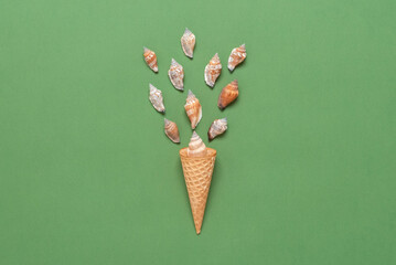 Seashells in a waffle cone for ice cream. Creative layout. Green olive pastel paper background. Top view, flat lay. Summer concept.